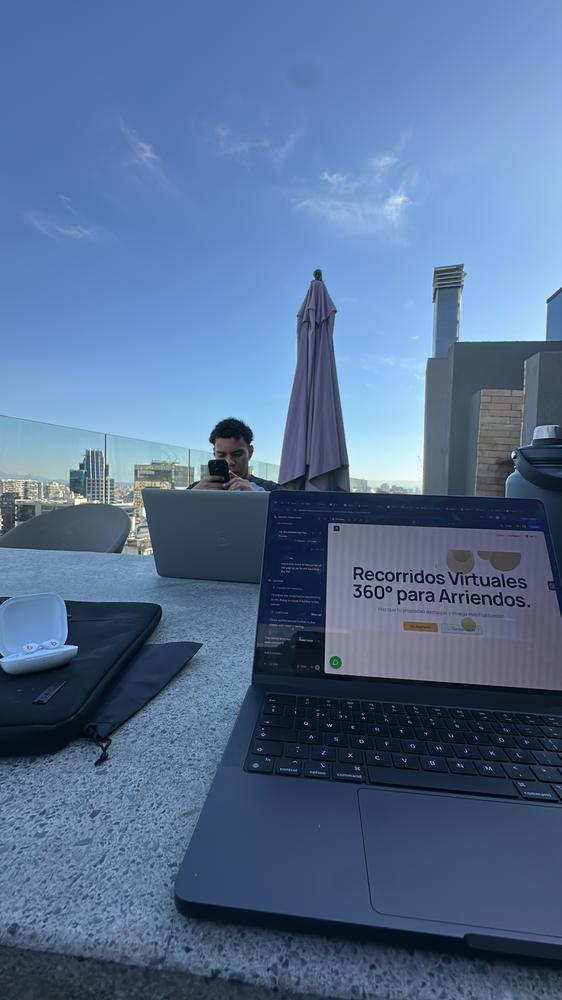 A laptop on a rooftop table in Santiago, showing the Castello360 site being built in Lovable