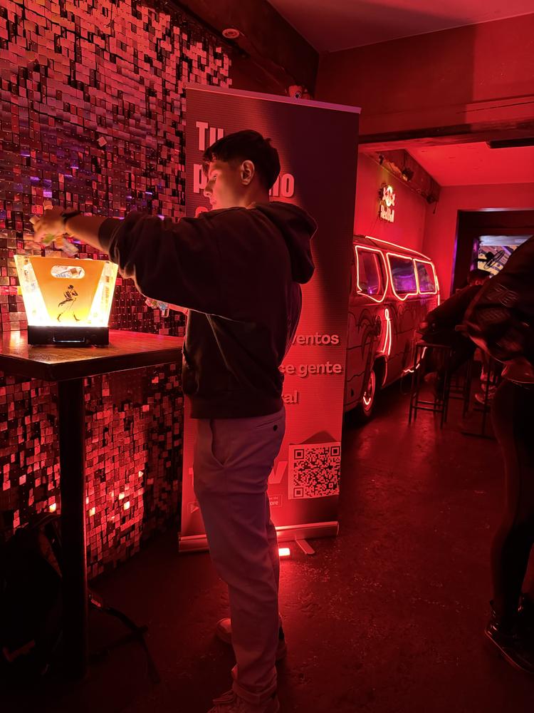 Luca pouring shots at a table beside a Toliv banner at a night event